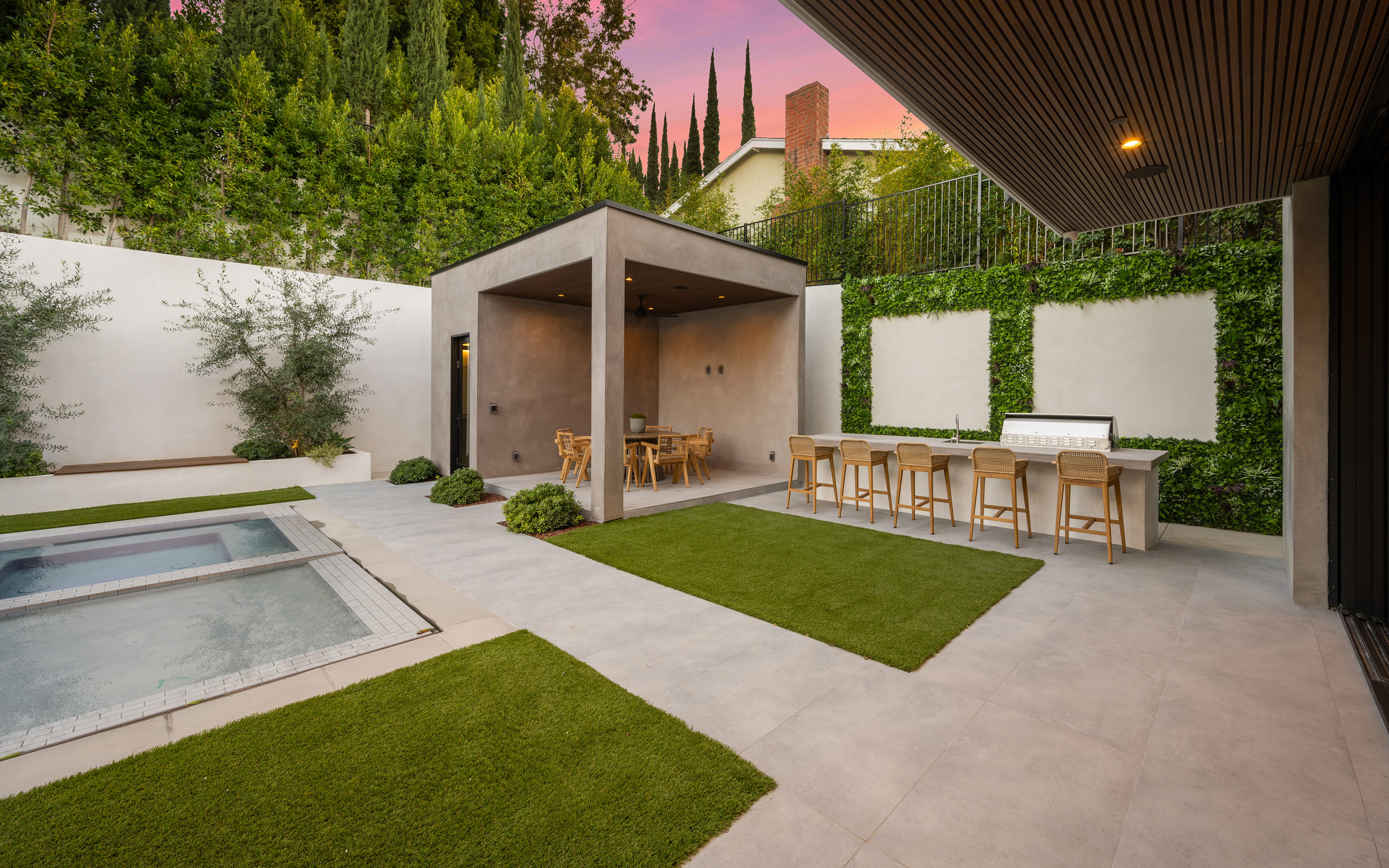An outdoor patio with a bar, pool, and overhead shading with concrete throughout.