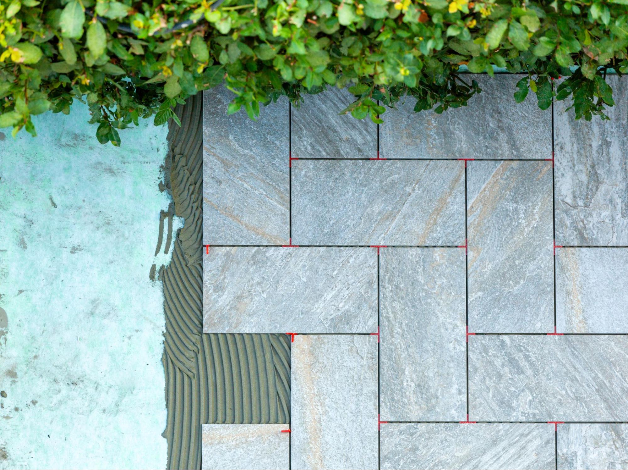 Porcelain pavers are set and spaced in an outdoor space under a shrub.