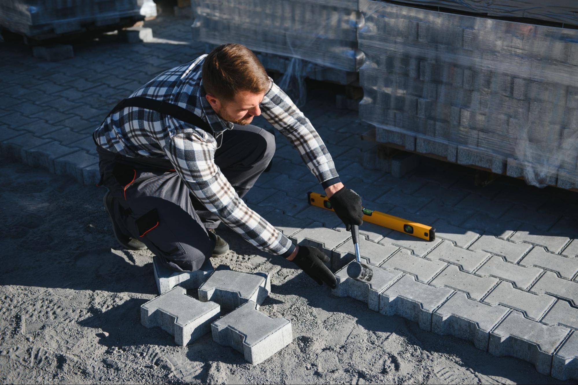 A builder taps pavers into place during an installation.