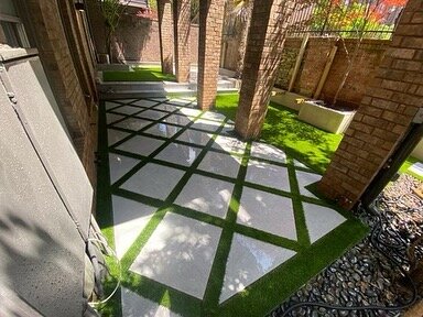 Courtyard with porcelain pavers and artificial grass. Stucco walls with porcelain caps.