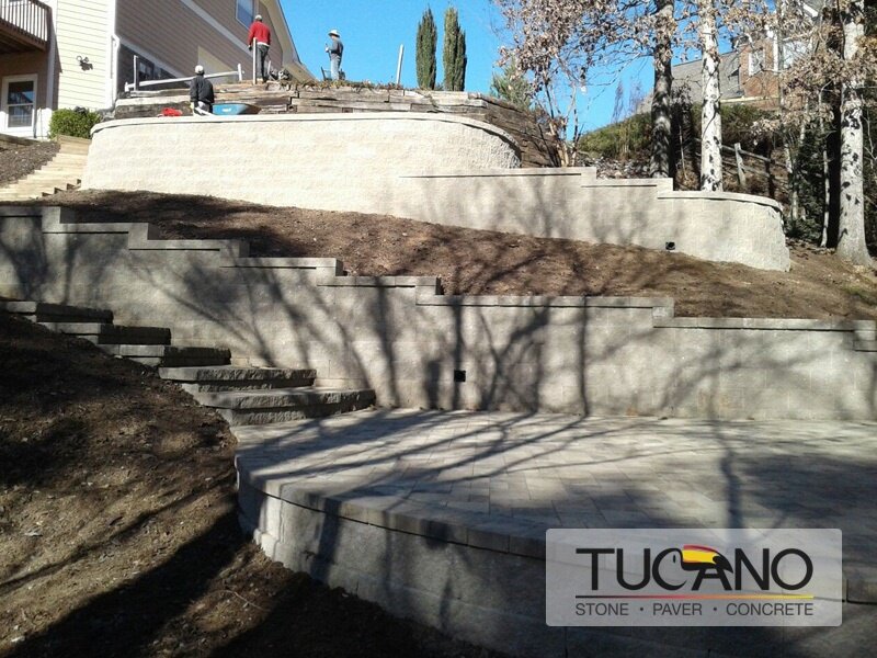 Wide retaining wall with Rockwood Classic grey blocks and caps, two section with tan stepping stones