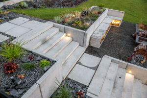 A freshly installed concrete staircase with retaining walls and accent lighting.
