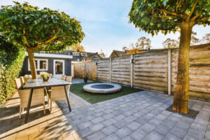 The sun begins to set over a fenced yard with earth-tone pavers installed.