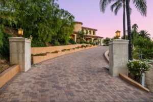 A luxurious modern home featuring a wide, custom paver driveway with clean lines and refined curb appeal.