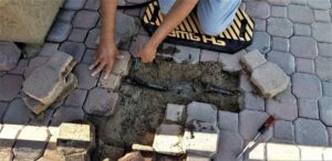 Overhead view of a paving contractor realigning patio pavers to restore surface stability